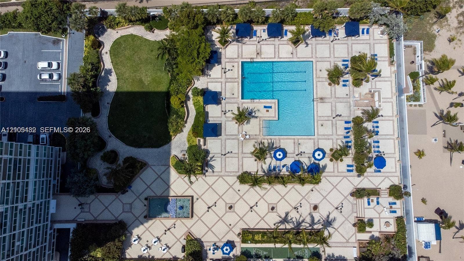2100 S Ocean Lane, #808, Fort Lauderdale, FL 33316 Aerial perspective of the common grounds featuring a lap pool with tiled decking, a rectangular reflecting pool, landscaped green space, and palm tree clusters