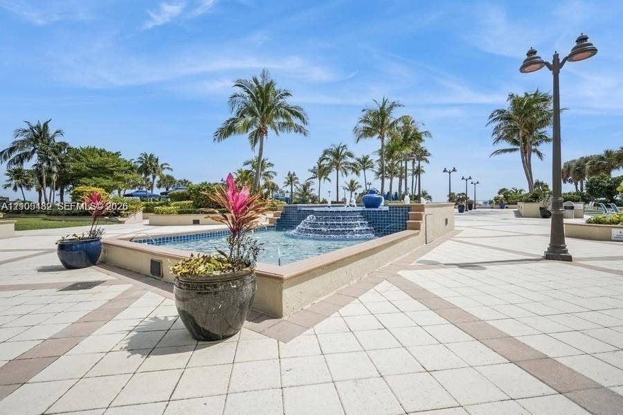 2100 S Ocean Lane, #808, Fort Lauderdale, FL 33316 Exterior courtyard featuring a tiered fountain with blue decorative tile, paved walkways, and mature palm trees