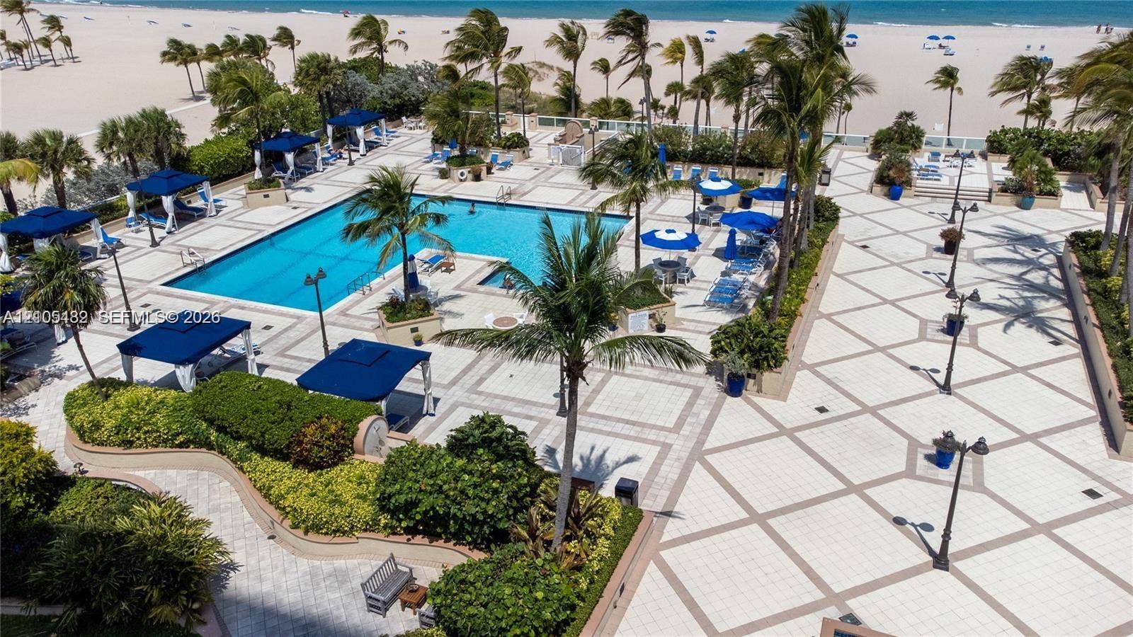 2100 S Ocean Lane, #808, Fort Lauderdale, FL 33316 Outdoor swimming pool featuring a paved pool deck, surrounding tropical landscaping, and pole-mounted lighting