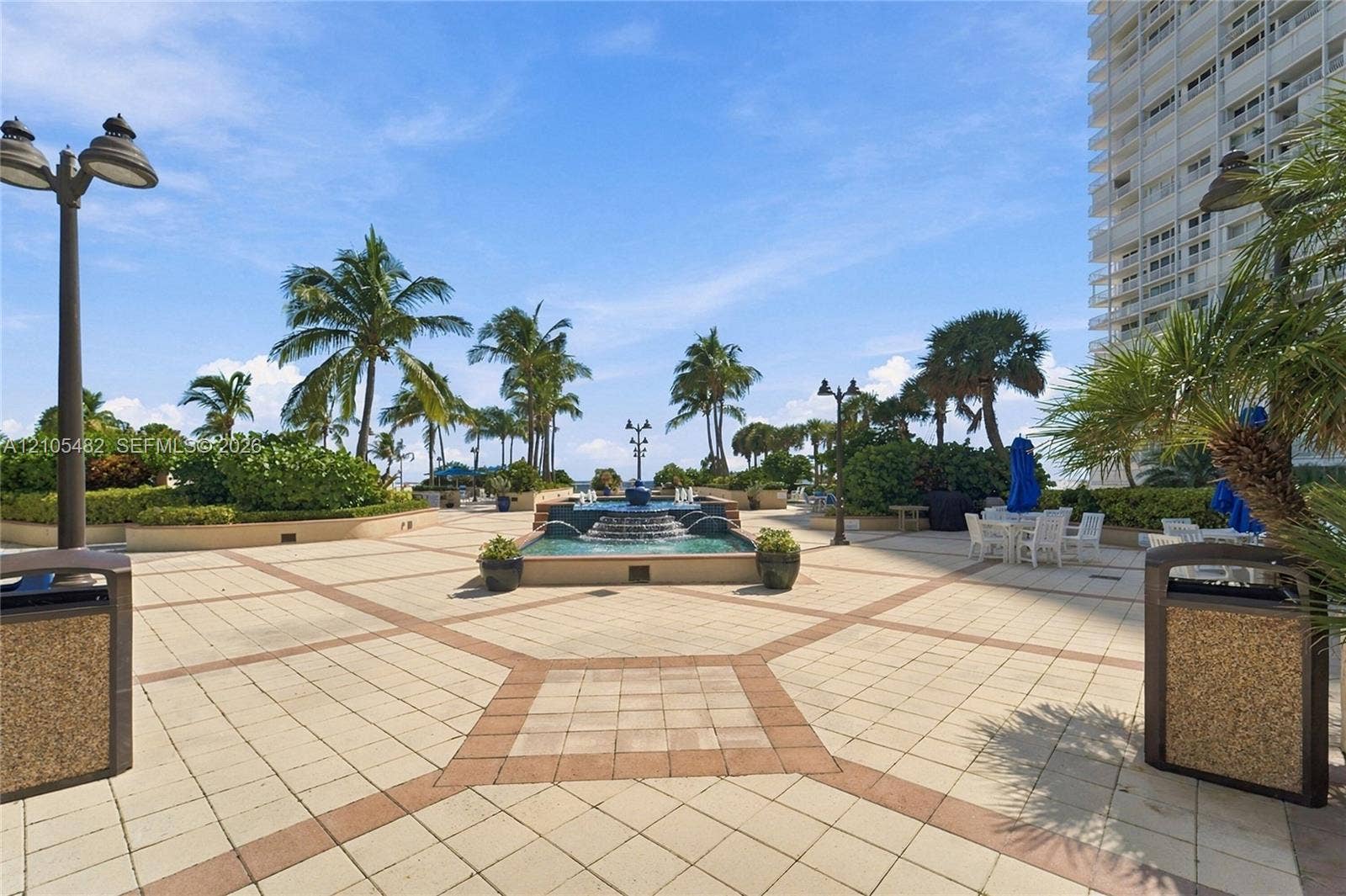 2100 S Ocean Lane, #808, Fort Lauderdale, FL 33316 Terrace featuring paver hardscaping, a multi-tiered stone fountain, mature palm trees, decorative post lighting, and built-in landscape planters
