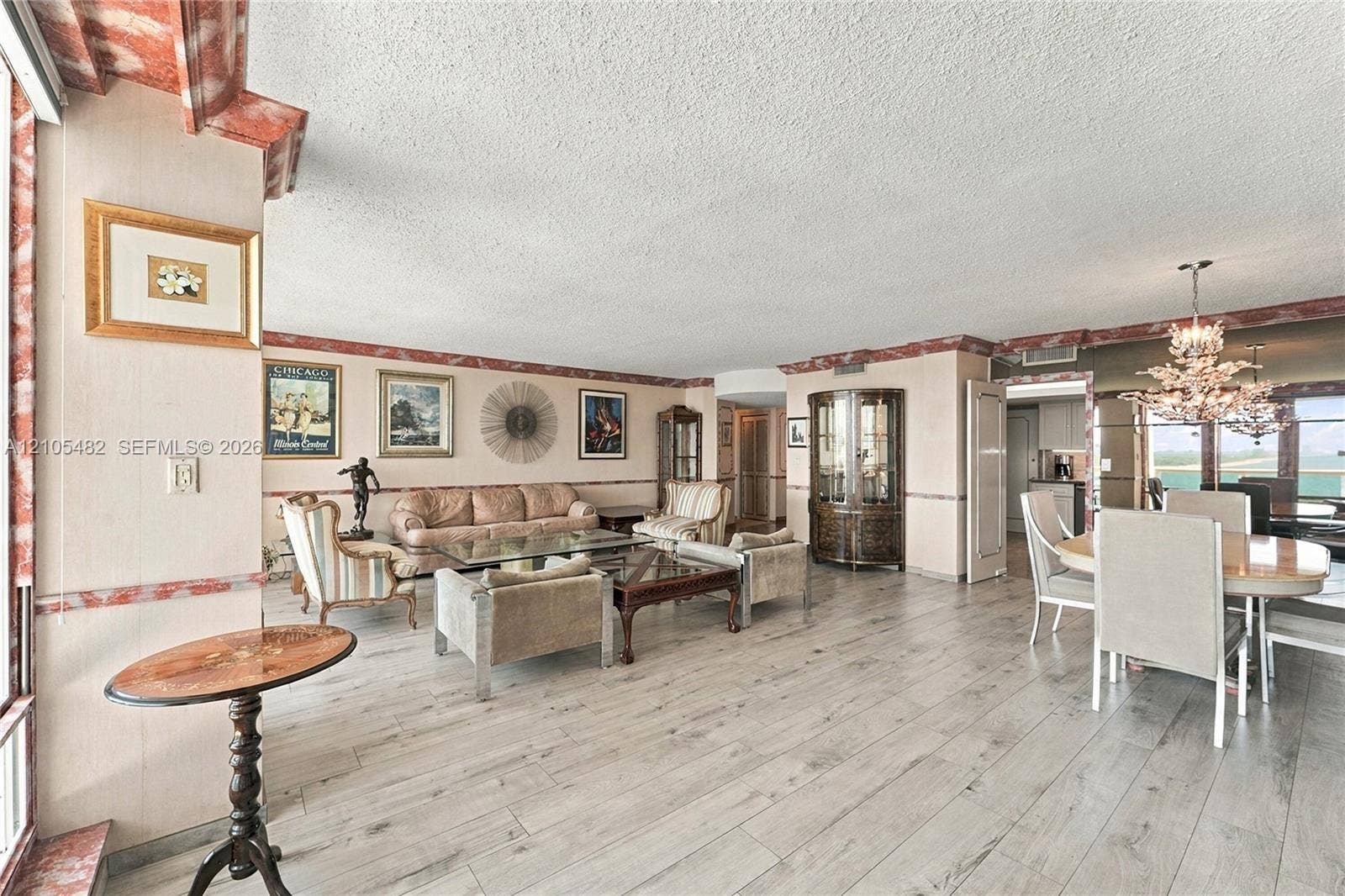 2100 S Ocean Lane, #808, Fort Lauderdale, FL 33316 Open-concept interior featuring wood-finish flooring, decorative crown and chair rail molding, built-in display cabinetry, and a tiered crystal chandelier