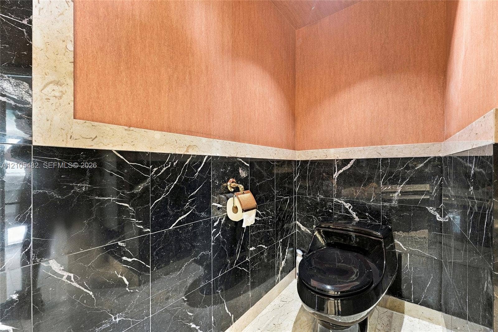 2100 S Ocean Lane, #808, Fort Lauderdale, FL 33316 Bathroom featuring black stone wall tiling, beige stone wainscoting, textured wall finish, and a black toilet