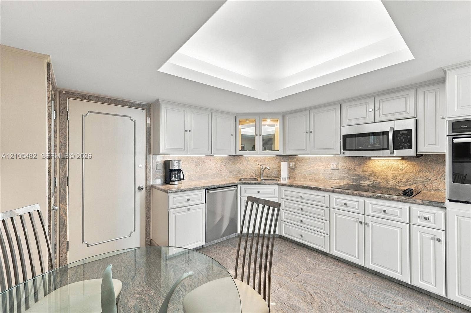 2100 S Ocean Lane, #808, Fort Lauderdale, FL 33316 Kitchen featuring white shaker-style cabinetry, stone countertops, stainless steel appliances, recessed tray ceiling, and stone flooring