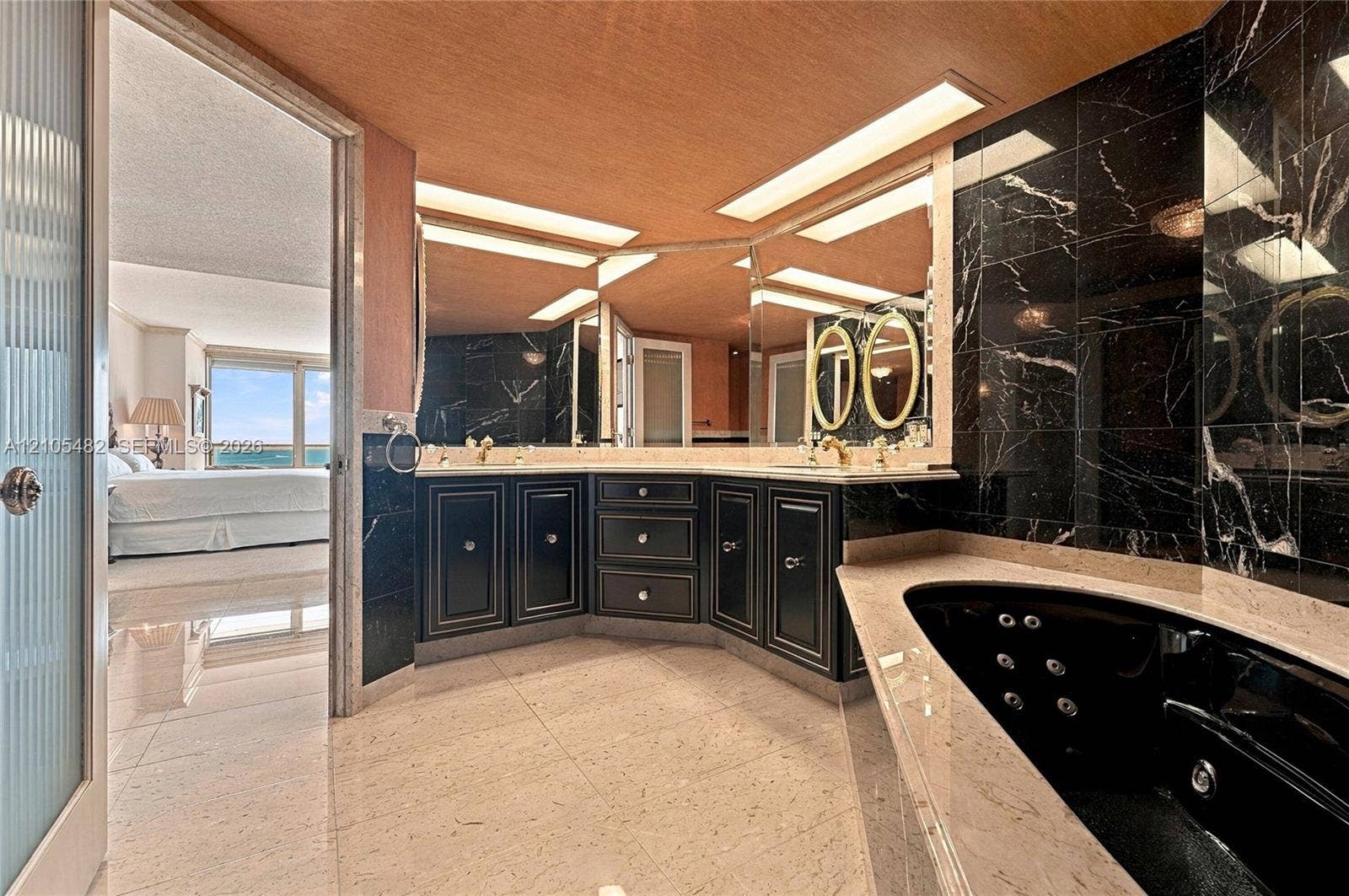 2100 S Ocean Lane, #808, Fort Lauderdale, FL 33316 Bathroom featuring a black soaking tub with jetted nozzles, stone-finish surround, dark cabinetry, recessed lighting, and a floor-to-ceiling mirror