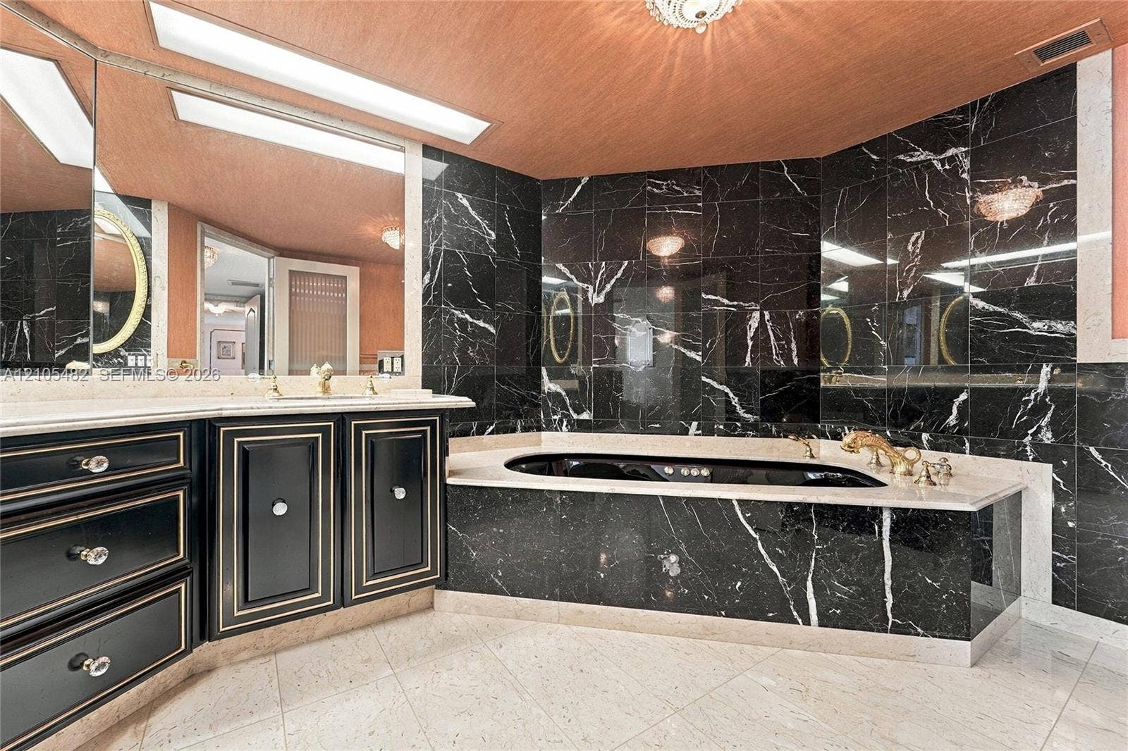 2100 S Ocean Lane, #808, Fort Lauderdale, FL 33316 Jetted soaking tub with stone surround, custom black cabinetry with metallic trim, light-toned stone flooring, full-wall mirrors, and recessed lighting