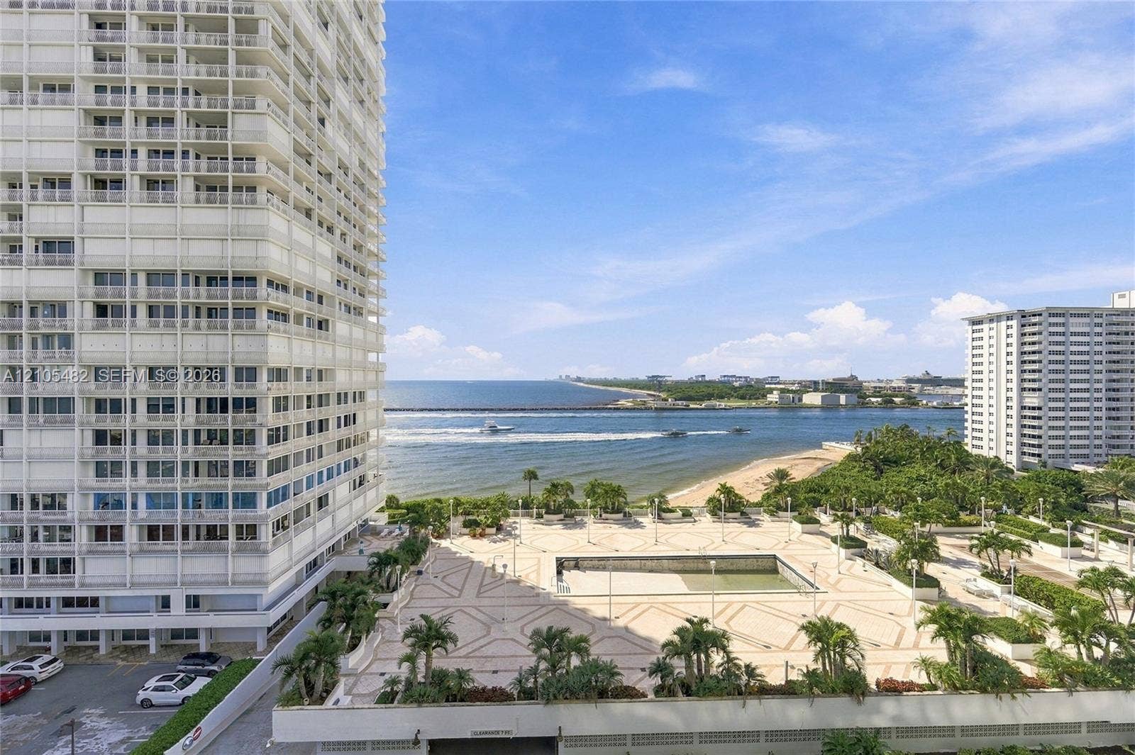 2100 S Ocean Lane, #808, Fort Lauderdale, FL 33316 High-rise exterior featuring integrated balconies, stone-tiled pool deck, mature palm landscaping, and expansive ocean and shoreline scenery