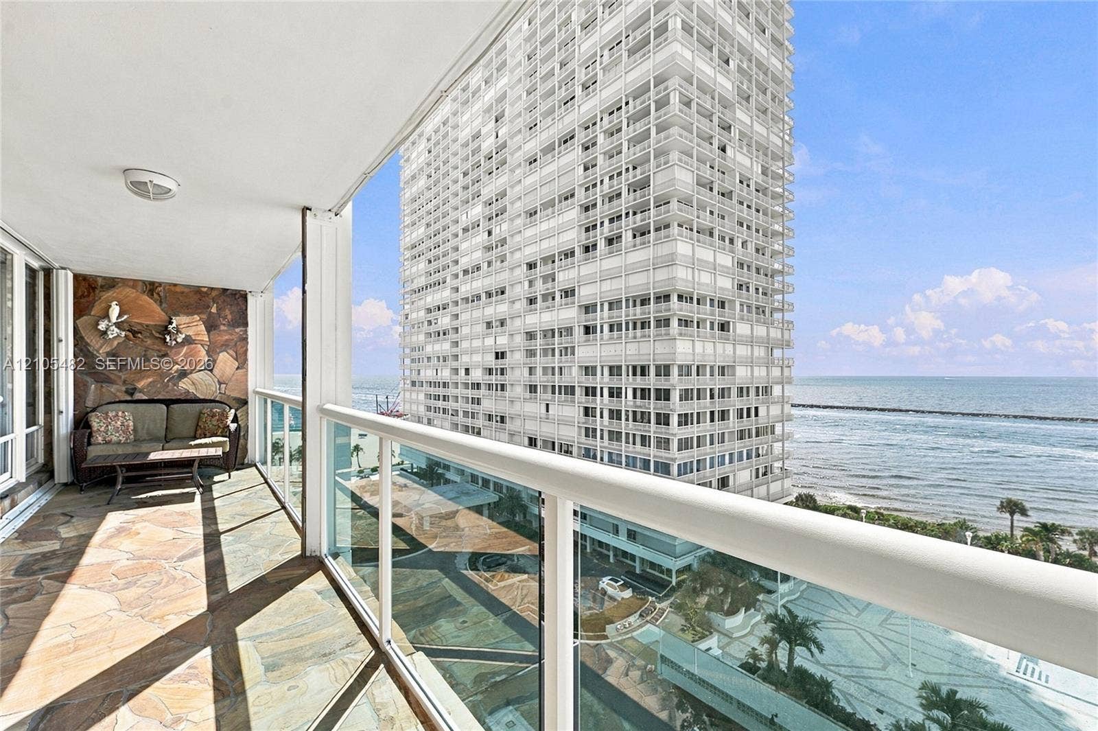 2100 S Ocean Lane, #808, Fort Lauderdale, FL 33316 Private balcony featuring natural stone flooring, a decorative stone accent wall, and glass panel railing with a metal handrail