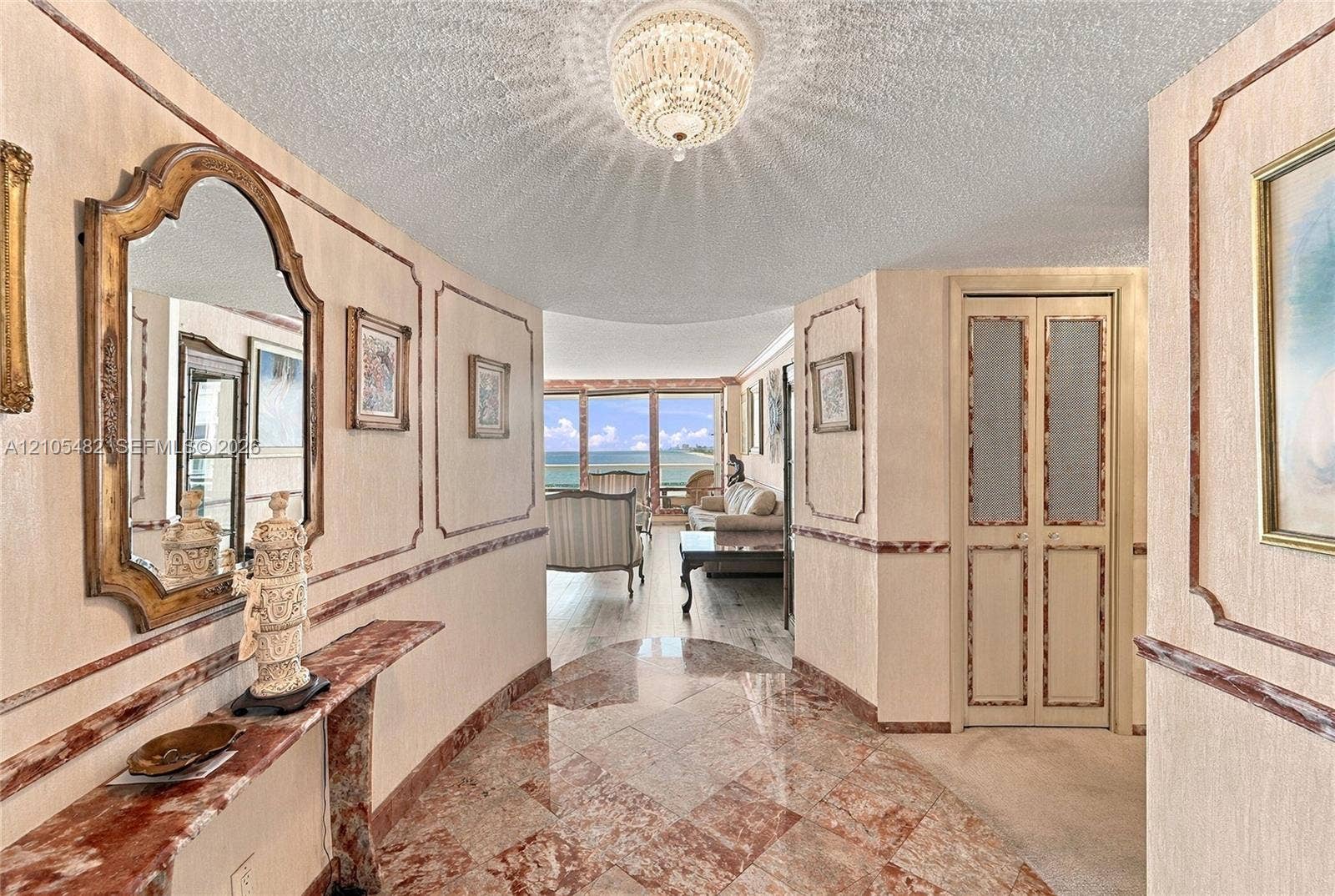 2100 S Ocean Lane, #808, Fort Lauderdale, FL 33316 Foyer featuring polished stone tile flooring, decorative wall molding, a tiered crystal ceiling fixture, and a built-in stone console