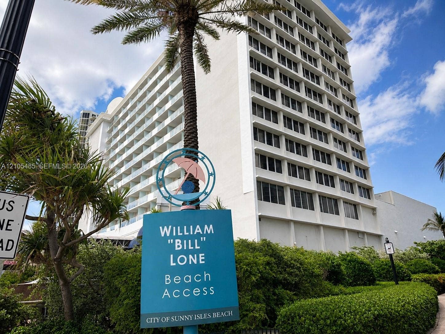 High-rise building exterior with multiple balconies, lush tropical landscaping, and a prominent palm tree
