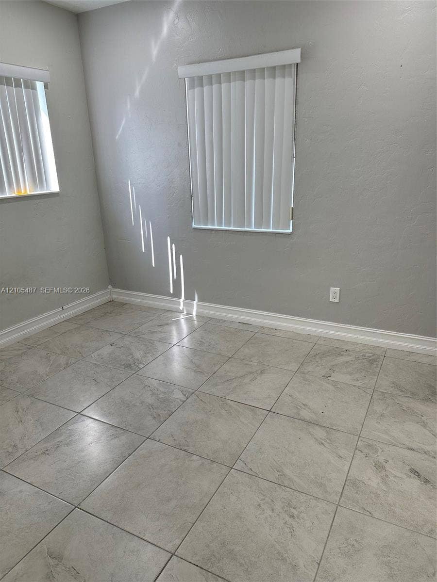 Ceramic tile flooring, white vertical blinds, and light gray wall finishes