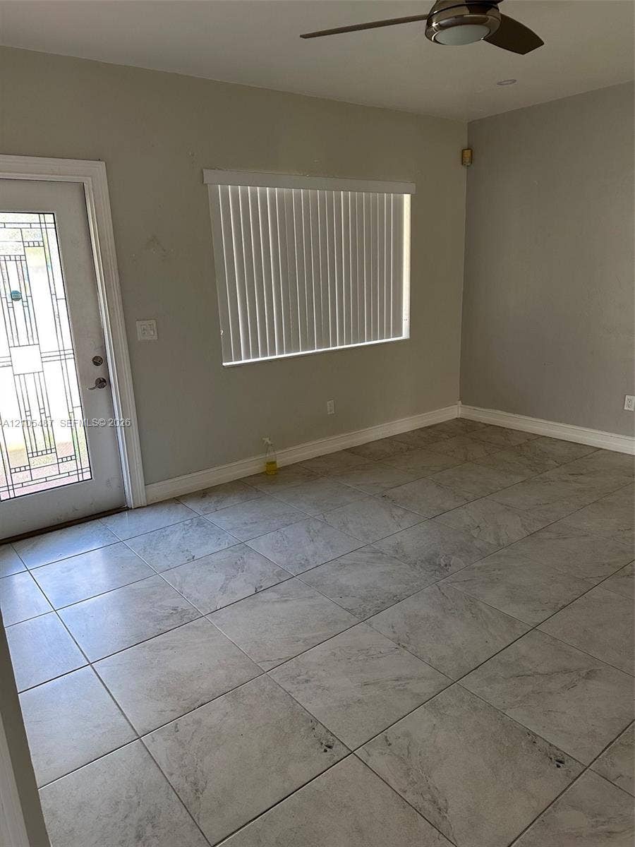 Tiled flooring, ceiling fan, window with horizontal blinds, and a door with decorative glass inserts