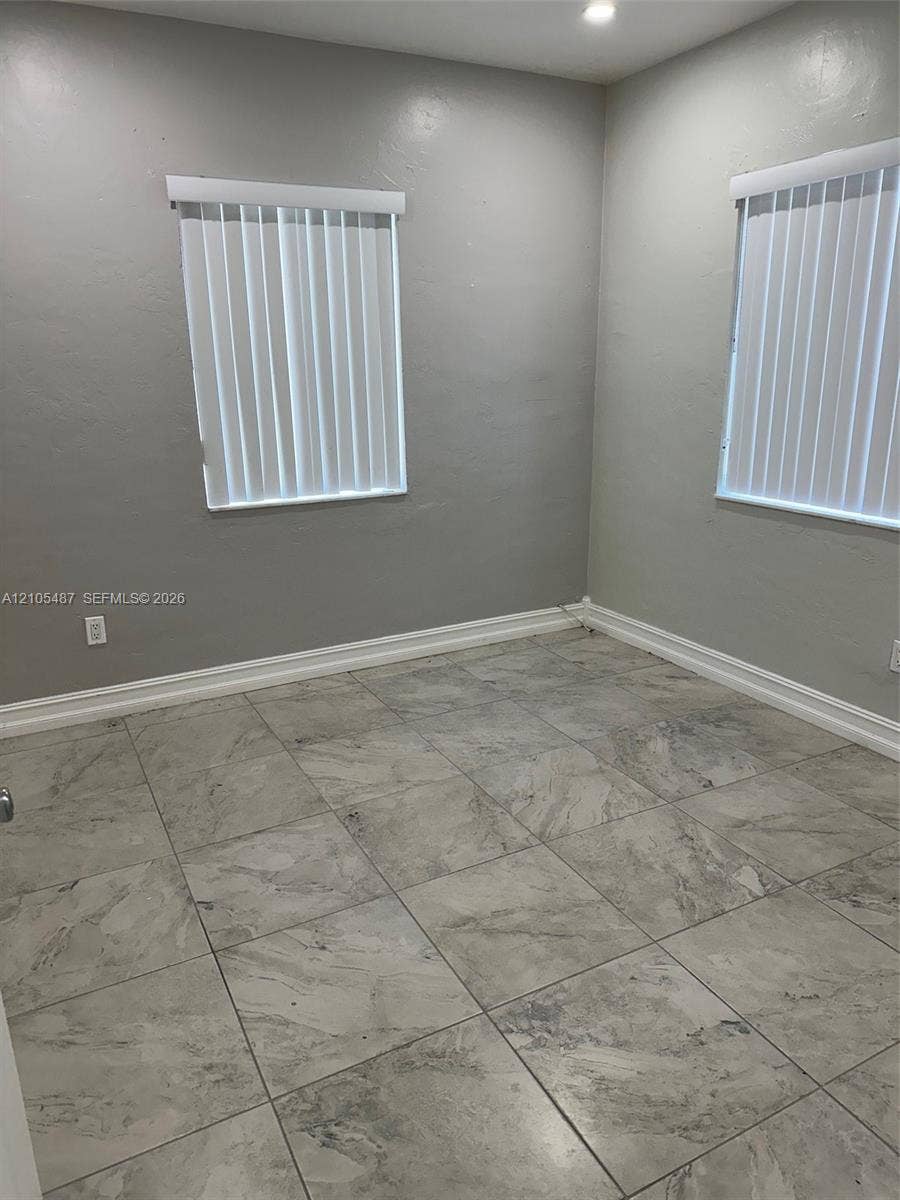 Recessed lighting, light gray wall finish, tile flooring, two windows with vertical blinds, and white trim