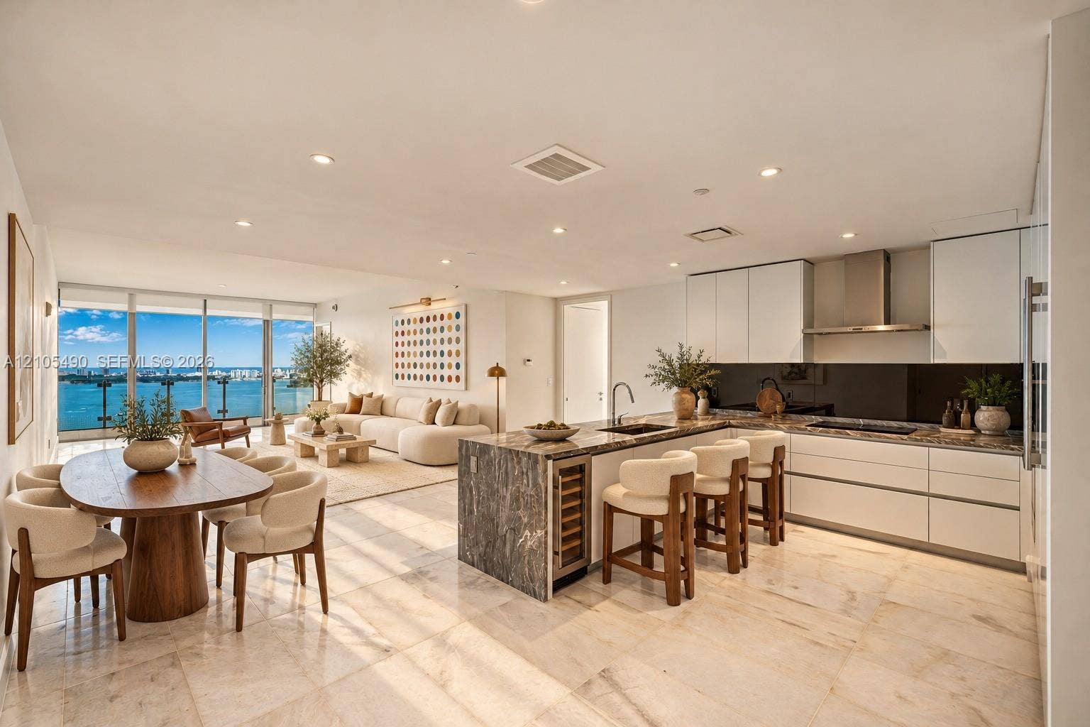 700 NE 26th Terrace, #3603, Miami, FL 33137 Open-concept living space featuring natural stone flooring, floor-to-ceiling windows, white flat-panel cabinetry, a stone-topped kitchen island with an integrated wine refrigerator, and a stainless steel vent hood