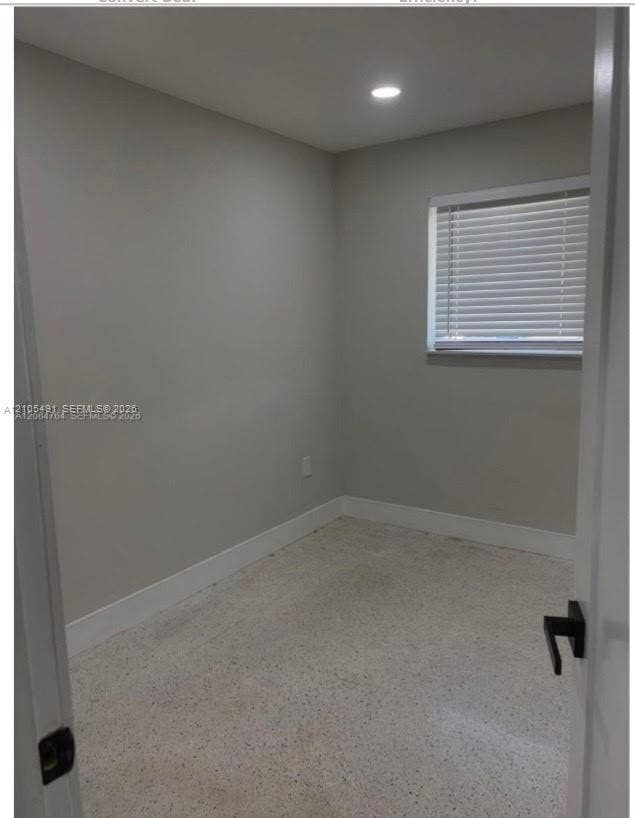 Recessed ceiling lighting, light gray wall paint, window with blinds, white trim, and speckled flooring
