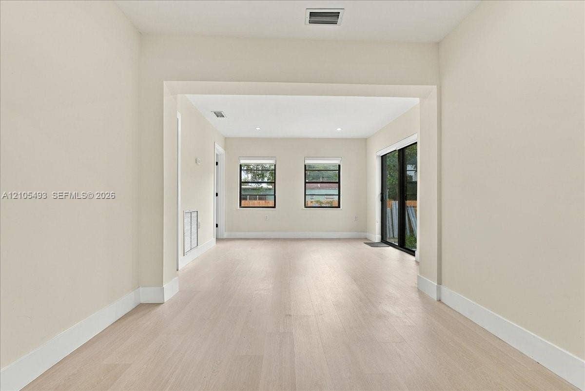Interior space featuring wood-finish flooring, recessed lighting, and sliding glass doors with black frames