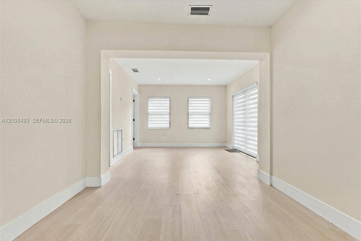 Interior space featuring wood-finish flooring, recessed lighting, and multi-paned windows with horizontal blinds