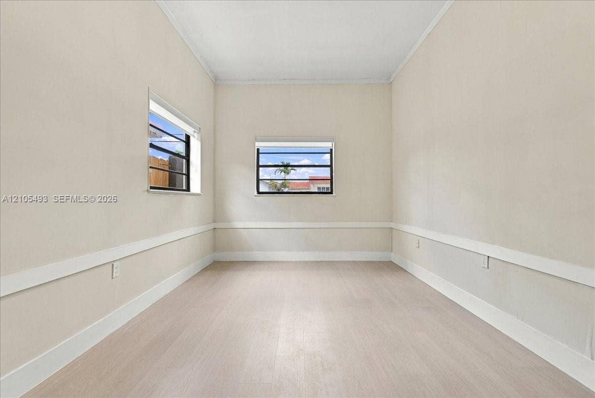 Neutral interior space featuring light-toned wood-finish flooring, white walls with chair rail molding, and horizontal sliding windows