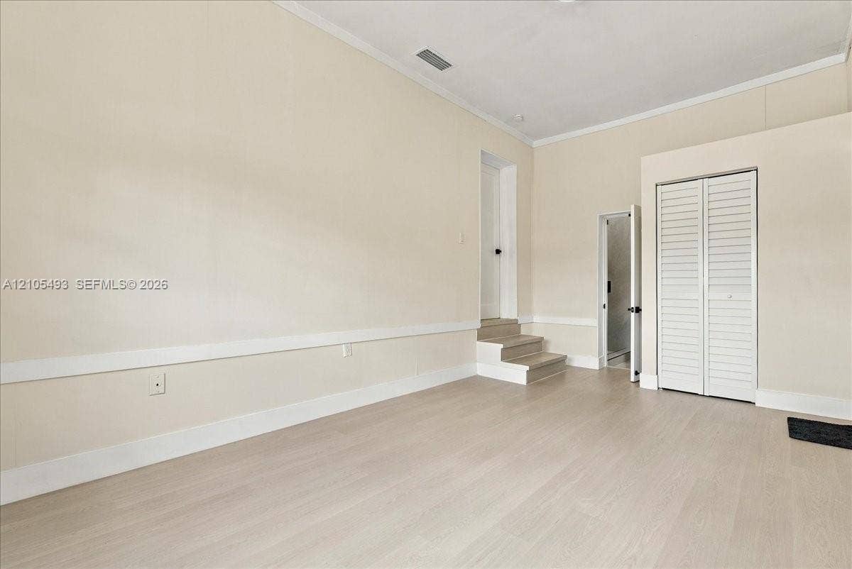 Interior space featuring wood-finish flooring, chair rail molding, louvered closet doors, and multi-level floor elevation