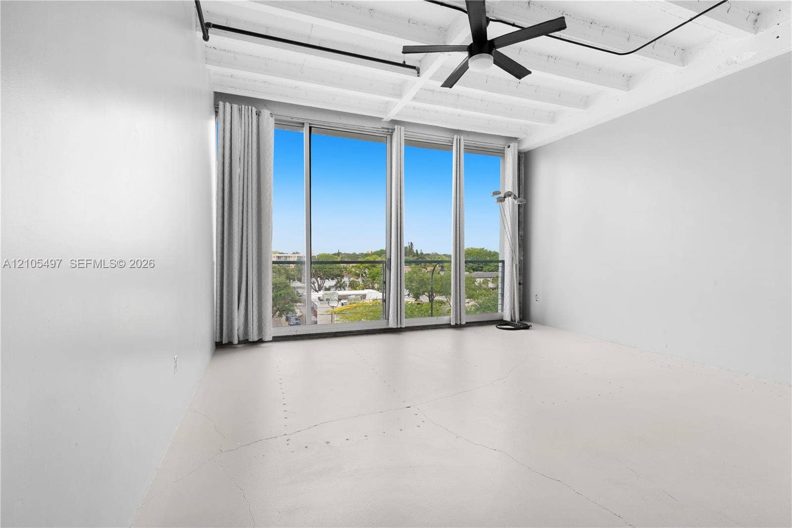 Expansive floor-to-ceiling windows, exposed beam ceiling, modern ceiling fan, and light-toned flooring