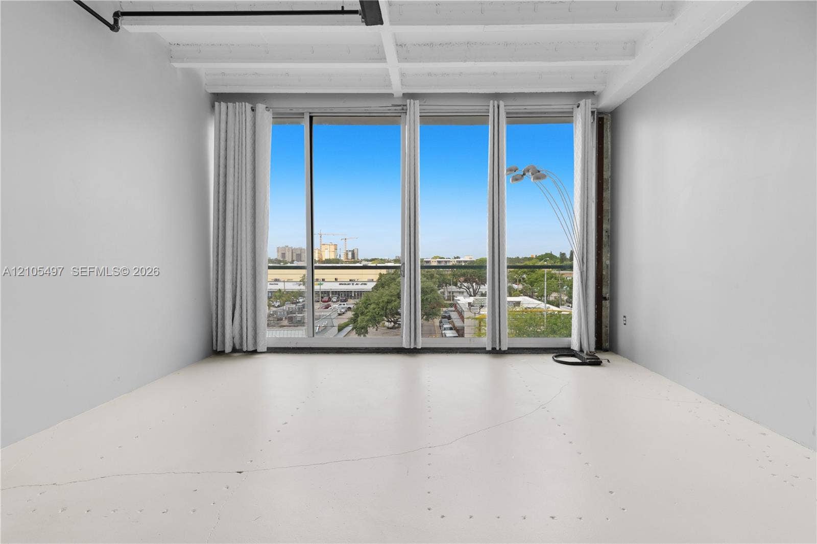 Expansive window system with vertical blinds, exposed ceiling beams, and industrial-style conduit