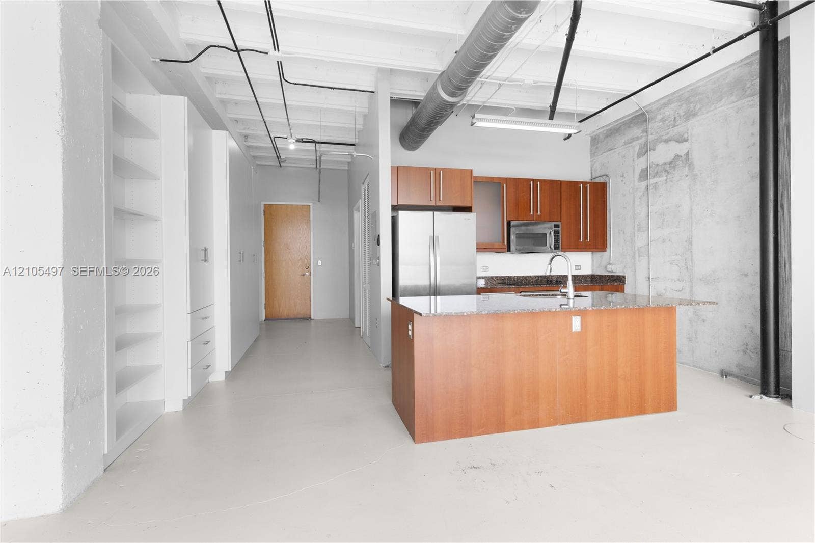 Kitchen featuring an island with a sink, stainless steel appliances, and wood cabinetry