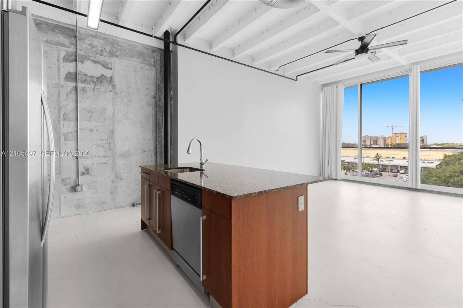 Kitchen island with a granite-style countertop, stainless steel sink, and dishwasher