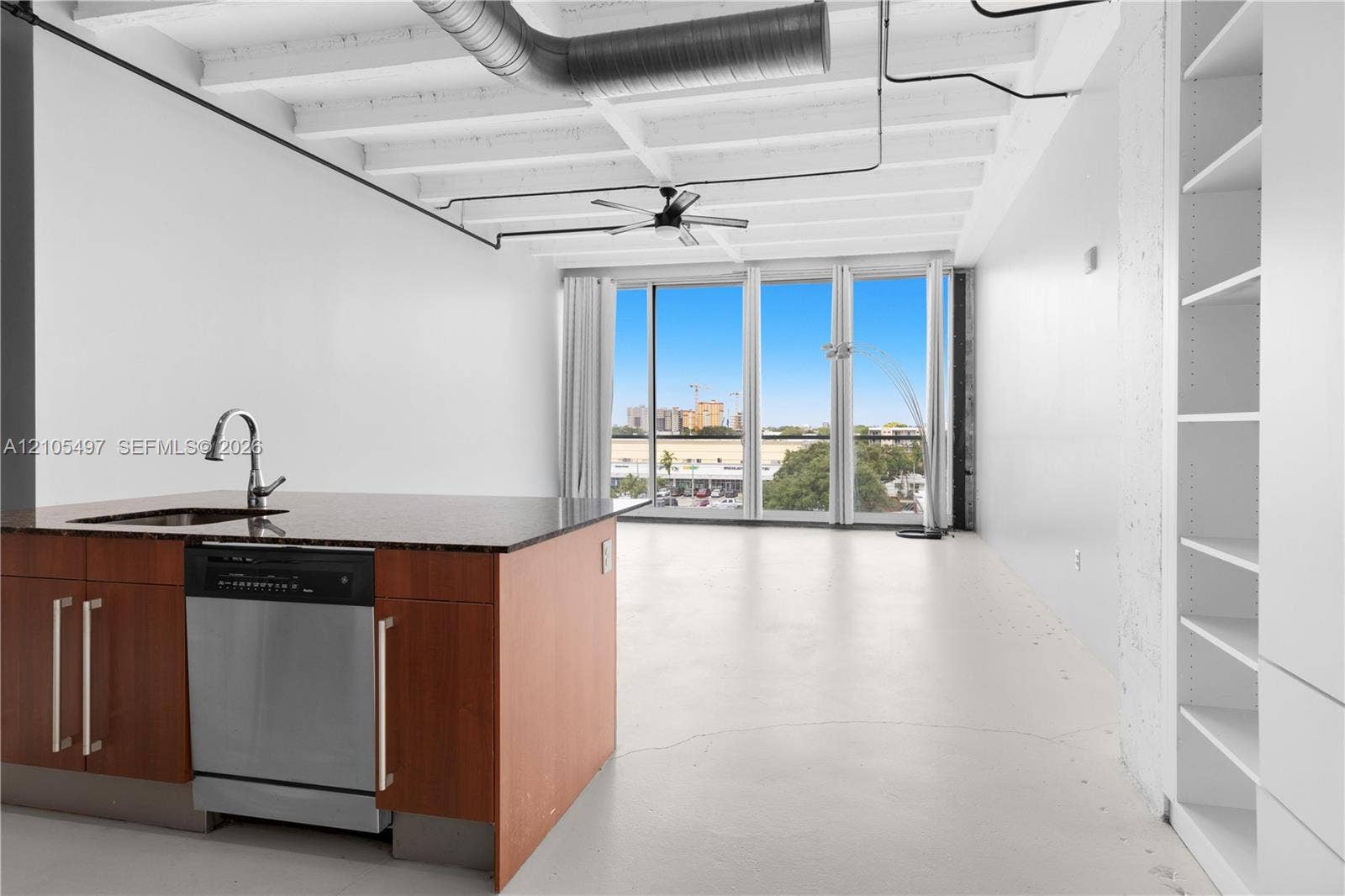 Kitchen island with dark countertop, stainless steel sink, and integrated dishwasher
