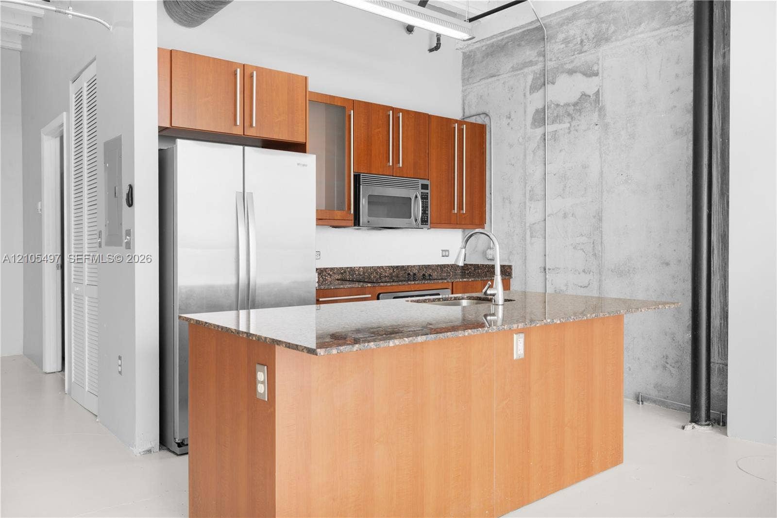 Kitchen featuring a central island, light wood-finish cabinetry, stainless steel appliances, and stone countertops