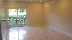 Sliding glass doors with balcony access, tile flooring, recessed lighting, and neutral wall tones