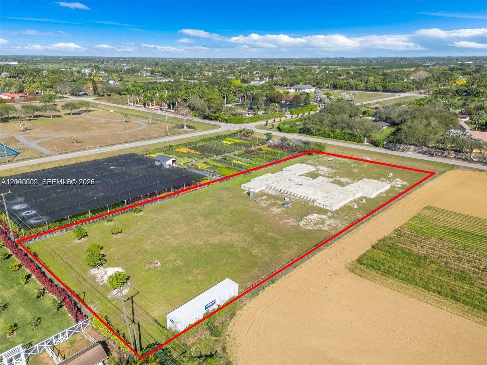 Expansive undeveloped lot featuring a concrete foundation, mature perimeter landscaping, and clear land boundaries
