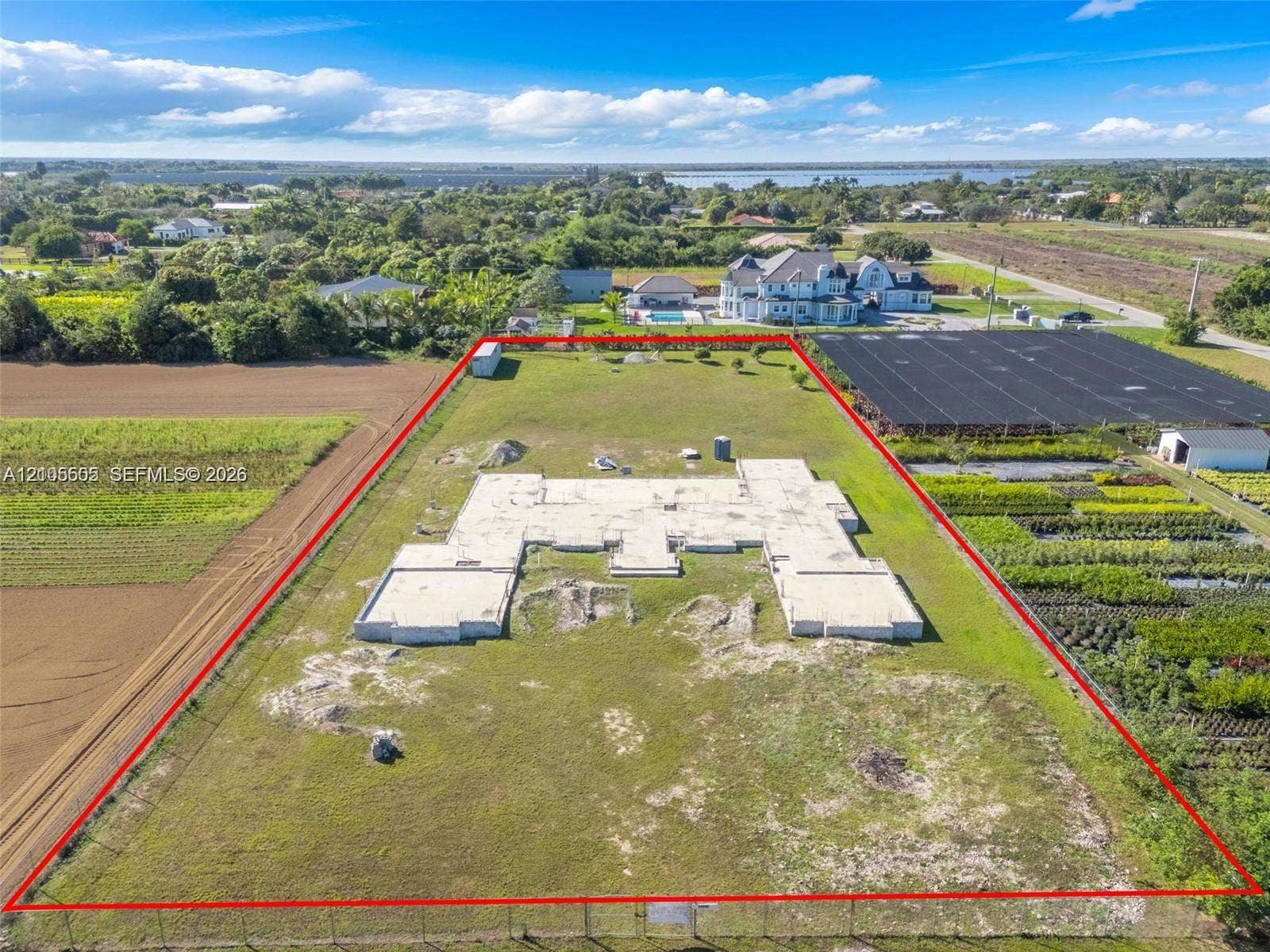 Expansive lot featuring a poured concrete foundation, perimeter fencing, and surrounding green space