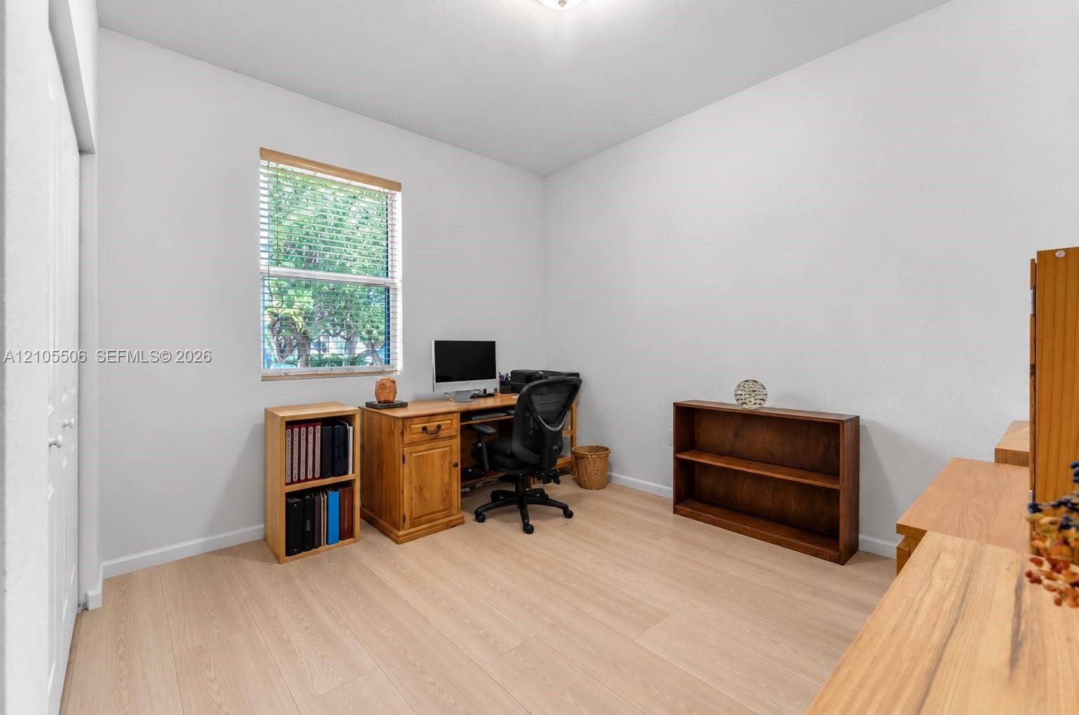 Neutral wall palette, light wood-finish flooring, and natural light from a window with horizontal blinds