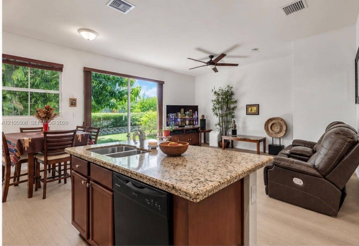 Kitchen island with granite countertop, double basin sink, and integrated dishwasher