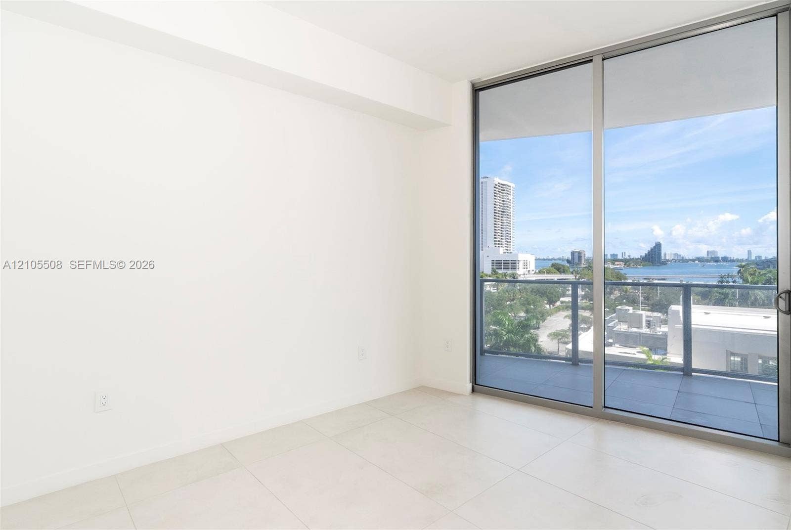 Sliding glass doors opening to a private balcony, offering expansive water and city scenery