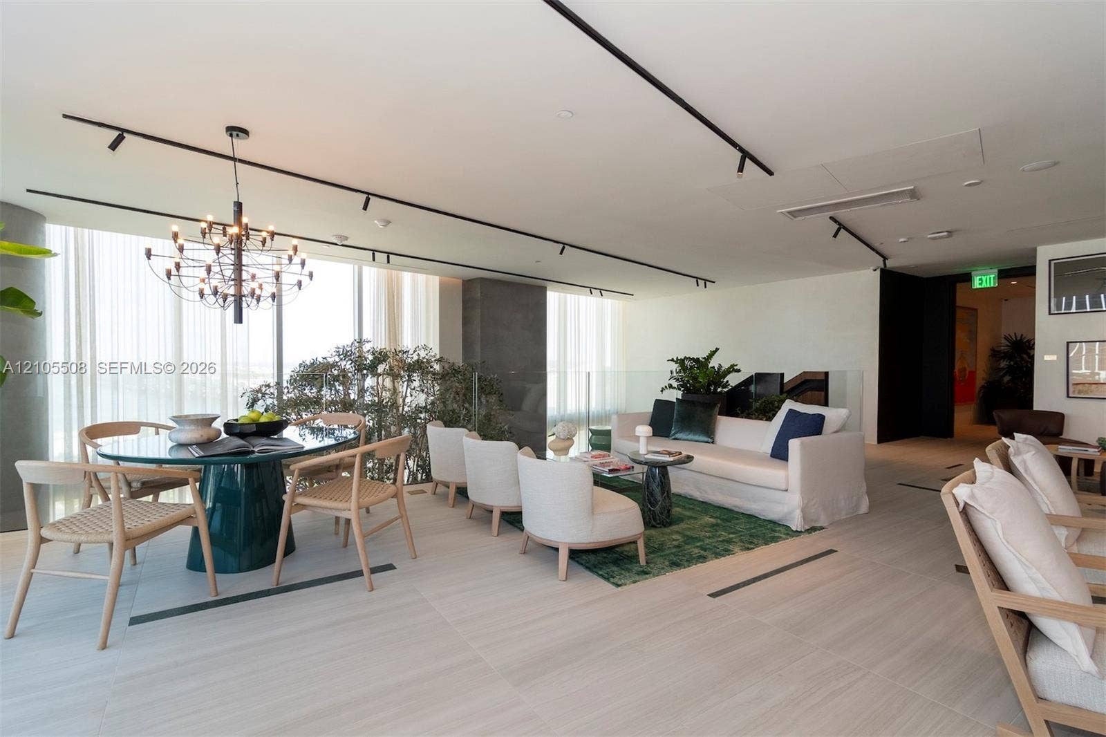Open-concept living space with expansive windows, a modern chandelier, track lighting, and light-toned tile flooring
