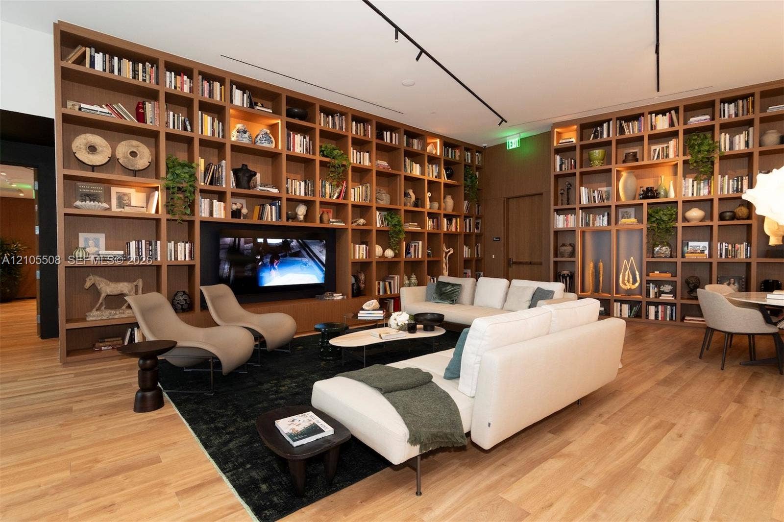 Built-in shelving with integrated lighting, wood-finish flooring, recessed ceiling lights, and track lighting