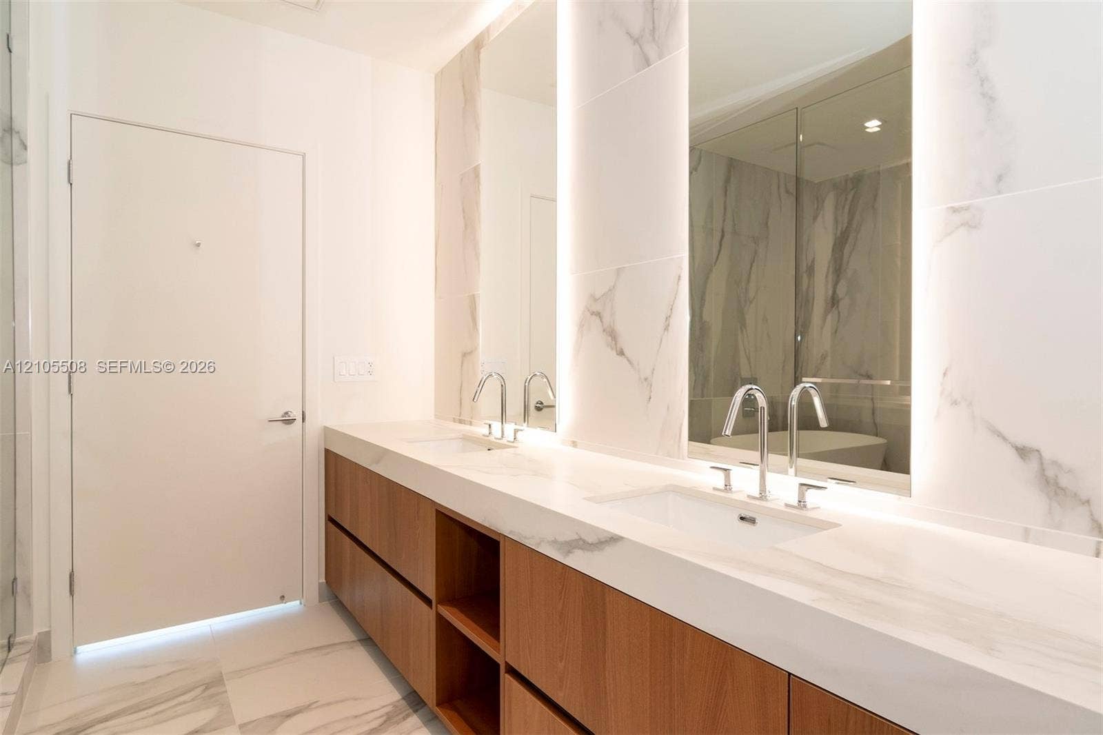 Dual undermount sinks with chrome faucets, integrated vanity lighting, and wood-finish cabinetry