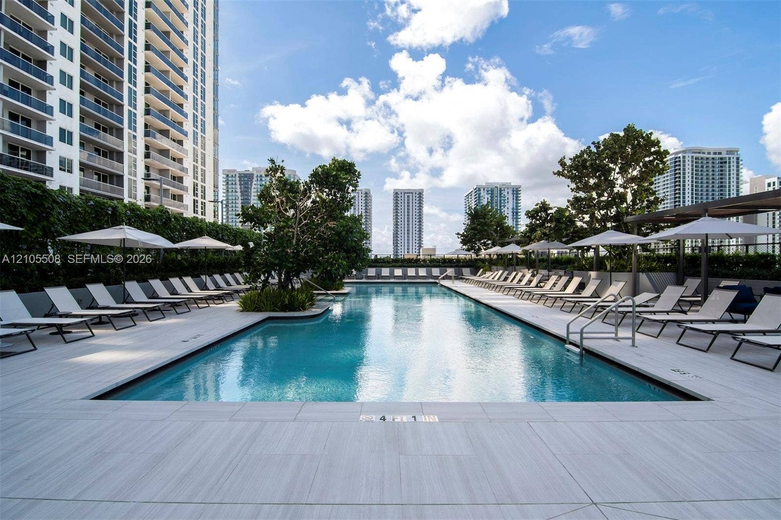 Expansive pool deck with a rectangular swimming pool, surrounding lounge seating, and mature landscaping