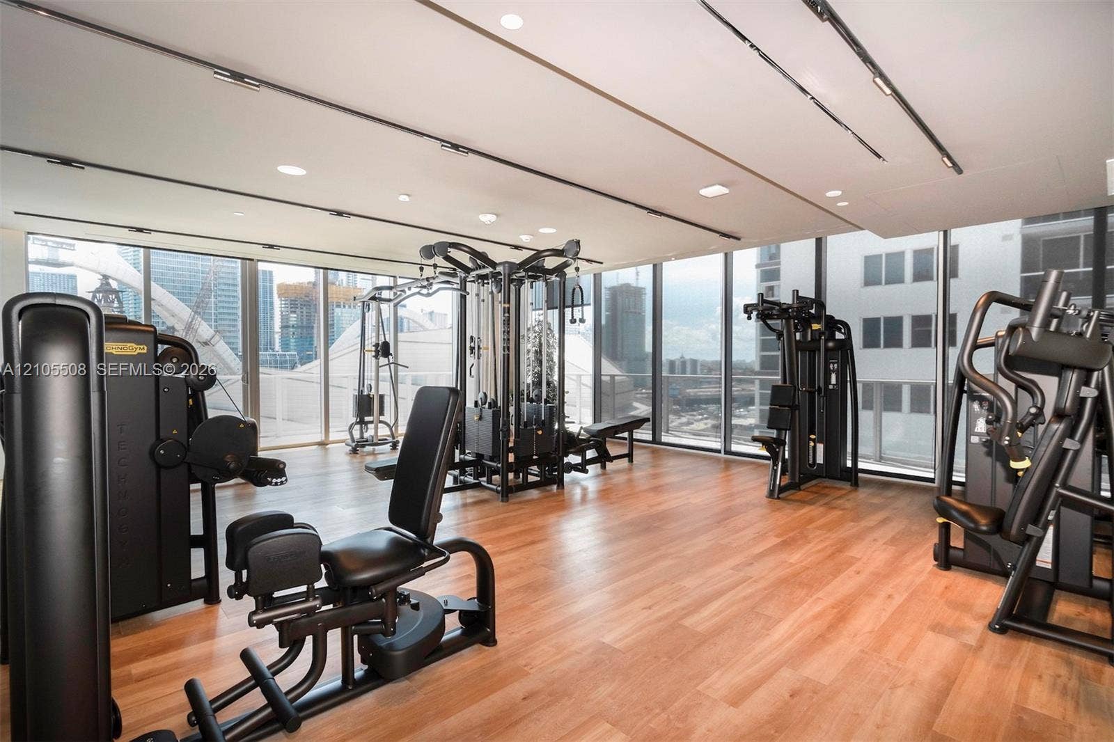 Fitness center with wood-finish flooring, recessed lighting, track lighting, and expansive window walls