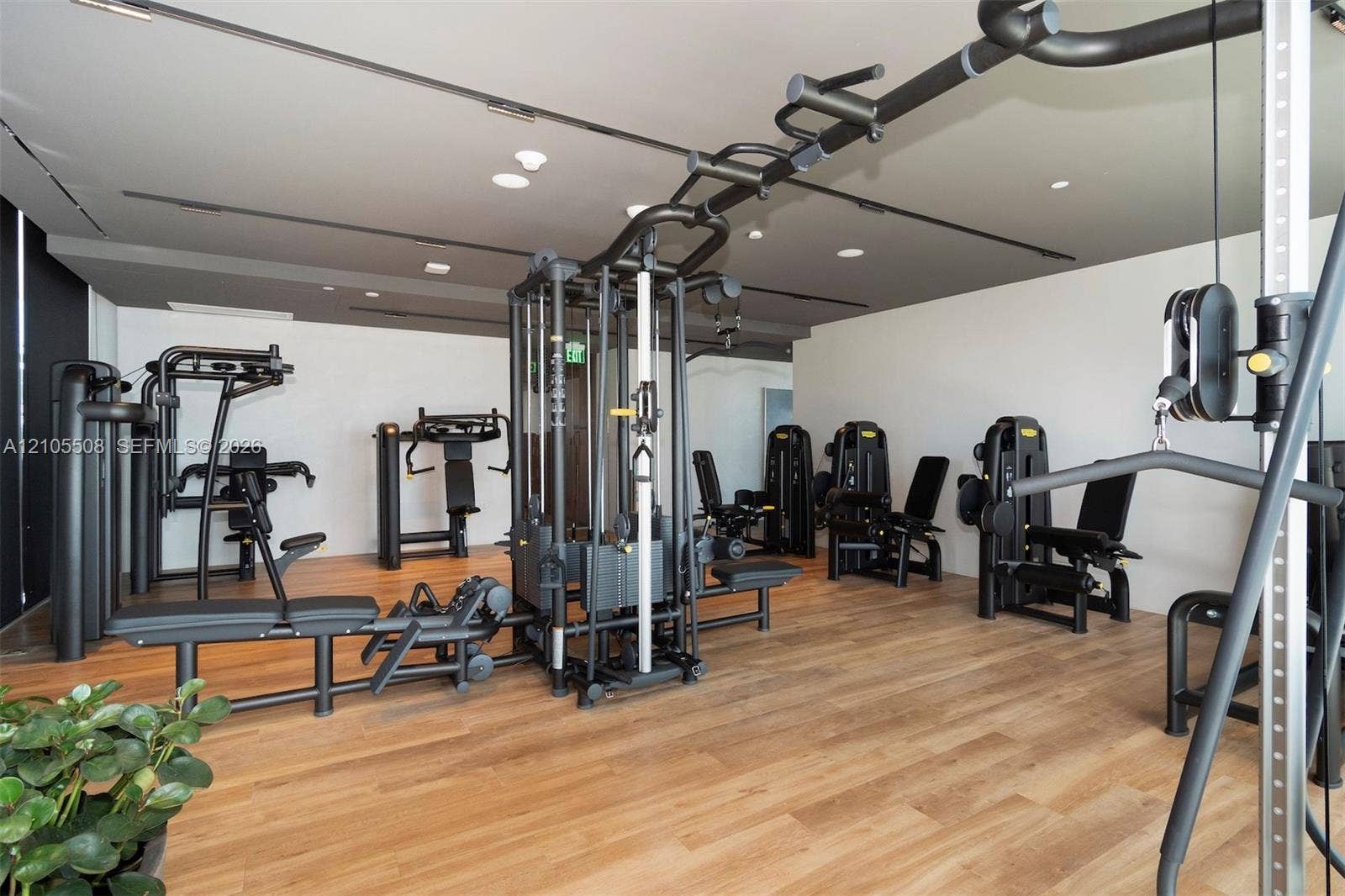 Dedicated fitness area featuring multiple exercise machines, wood-finish flooring, recessed lighting, and track lighting