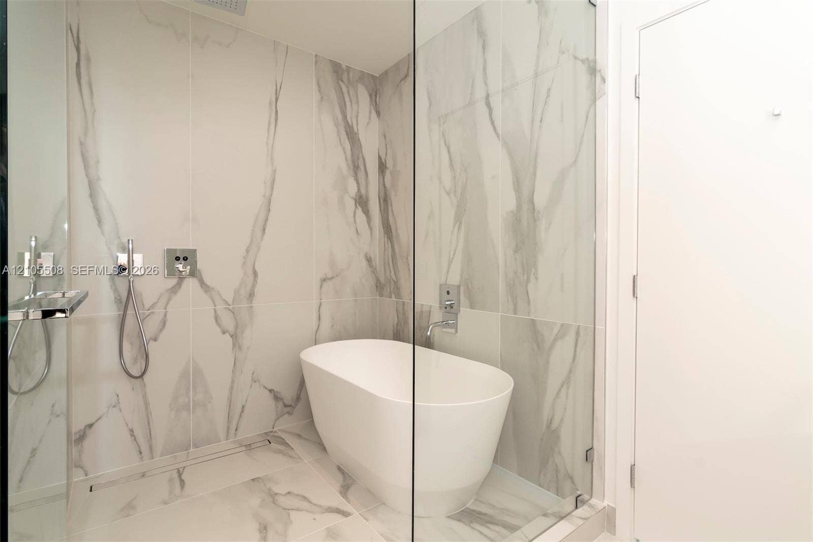 Freestanding tub within a glass-enclosed shower, featuring large format wall and floor tiling, and polished chrome fixtures