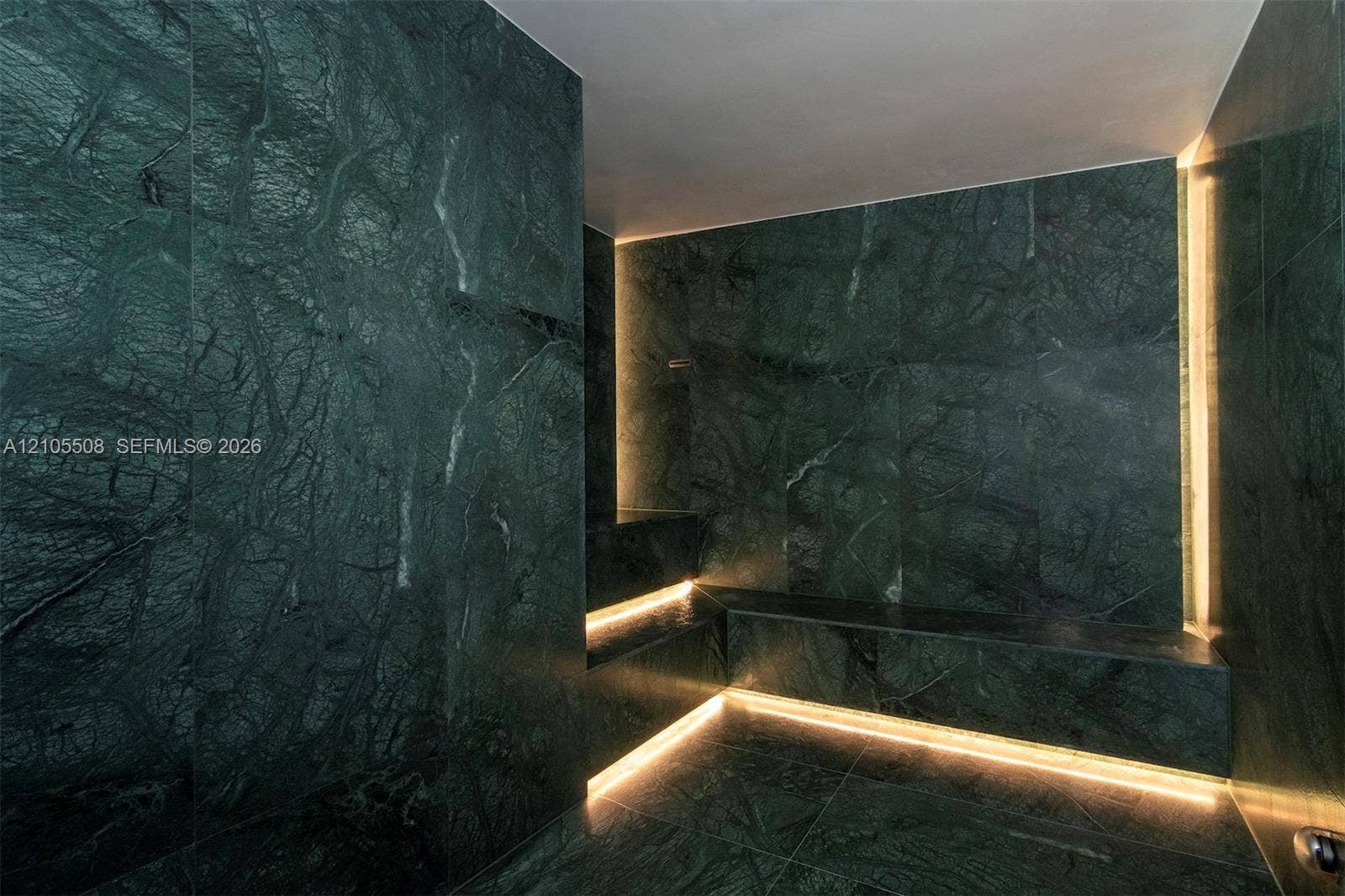 Green marble-style tile walls and flooring with integrated linear lighting