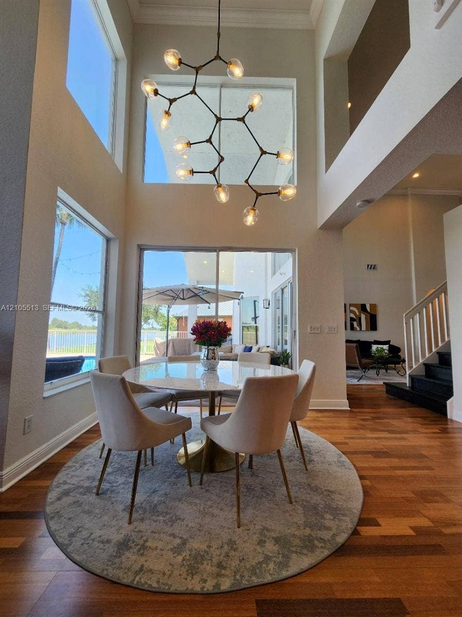 20ft vaulted ceilings with crown molding and an architectural chandelier & expansive windows allowing natural light to flood the room.