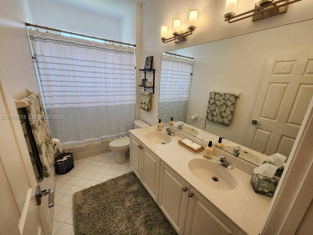 2nd Floor Guest Bath w/Dual vanity and extensive countertop space, complemented by two three-light sconce fixtures, a full-width wall mirror, and white panel cabinetry