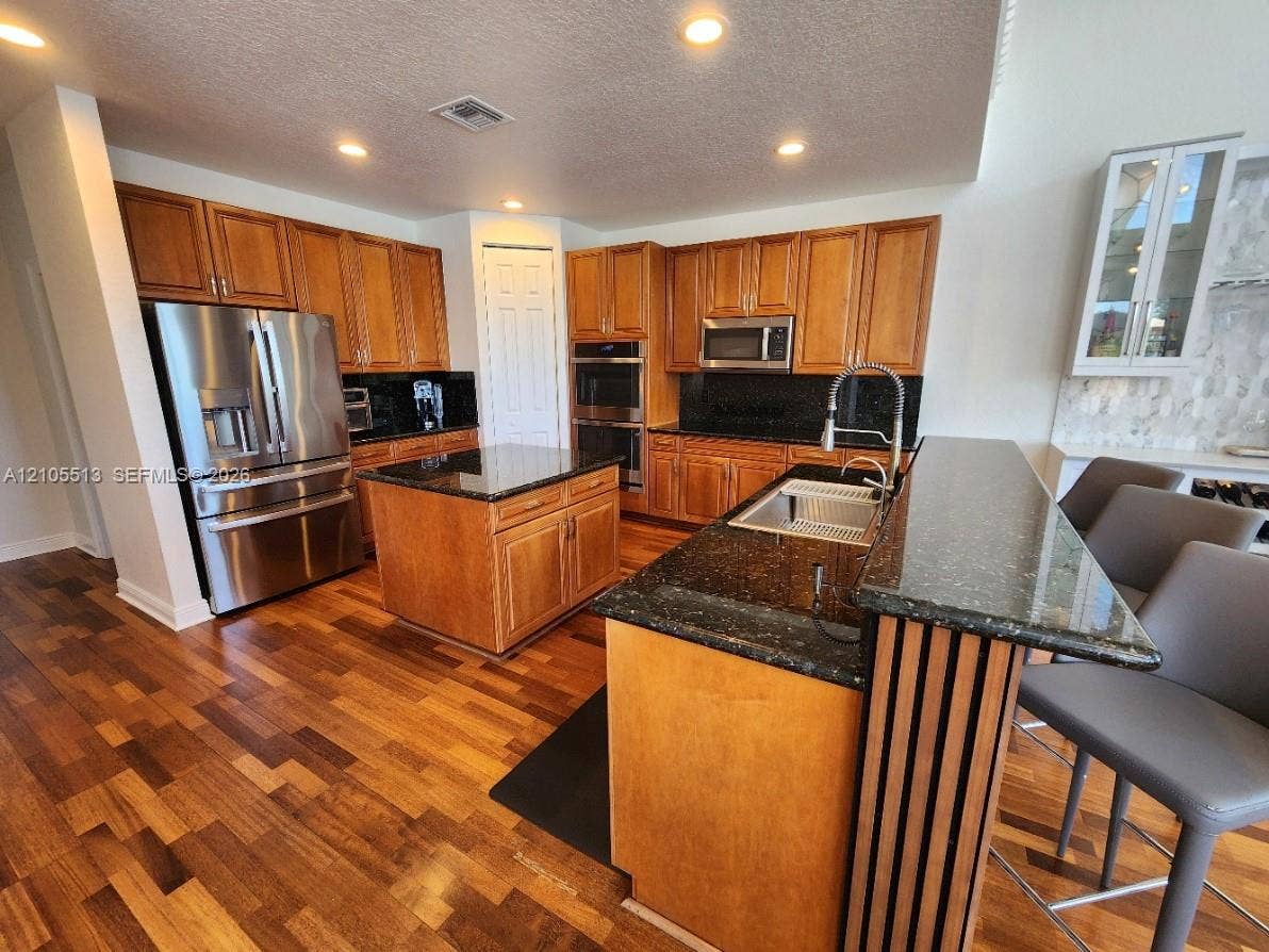 A center prep island and sink island with bar top dining area
