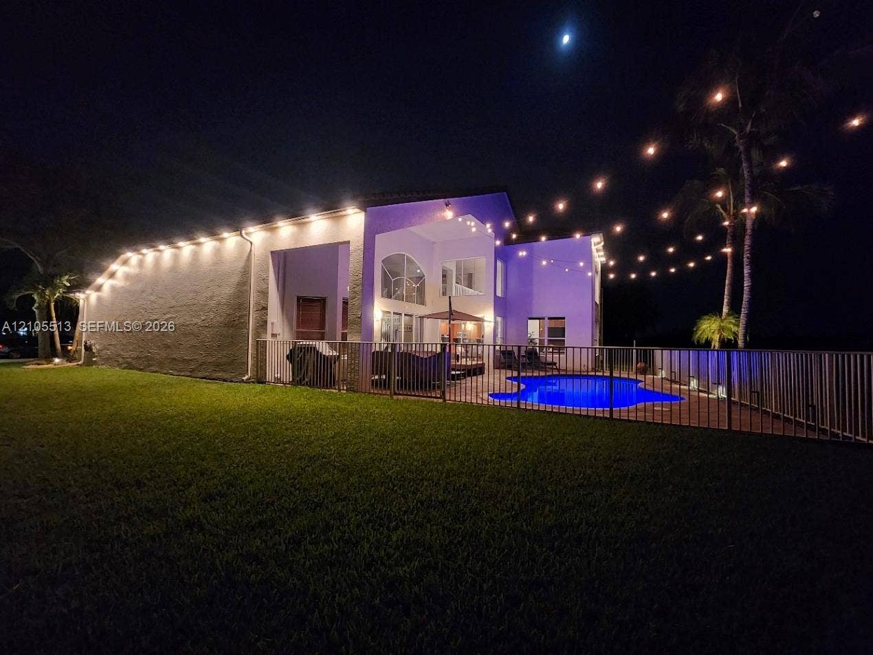 Night view of side with automated security down lighting, low voltage string lights & multi-colored pool light