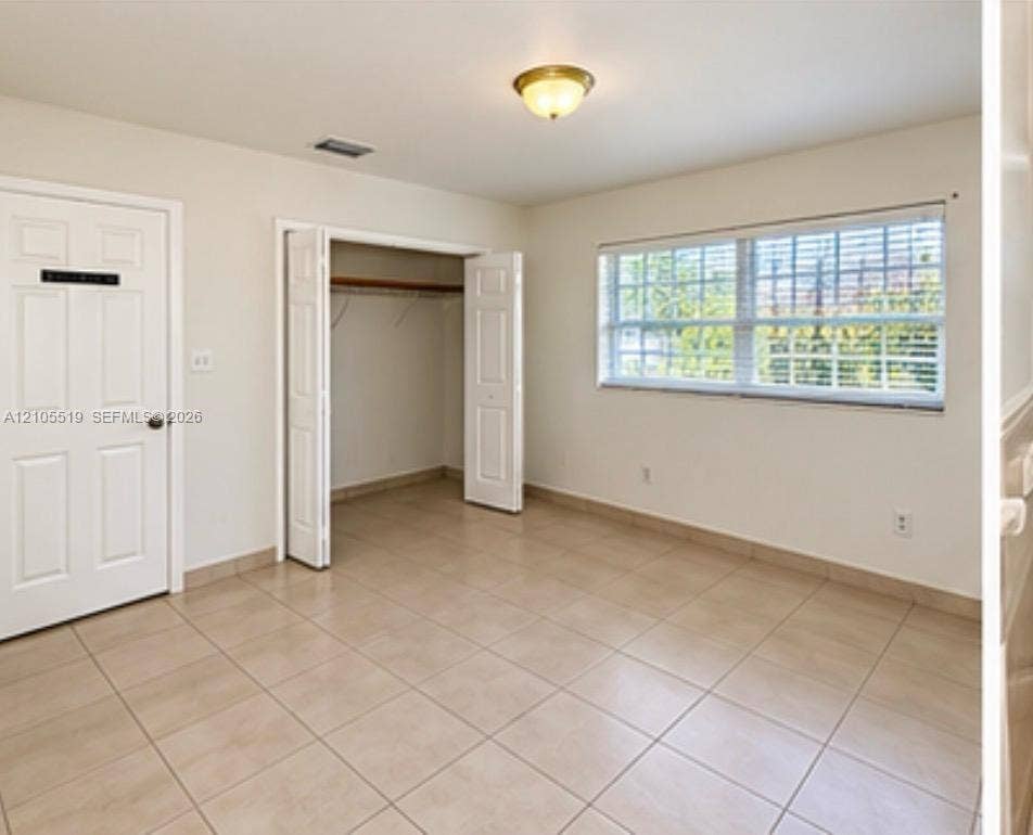Recessed lighting, tile flooring, window with blinds, bi-fold closet doors, and solid panel interior doors
