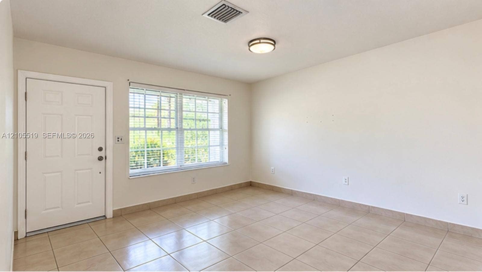 Ceramic tile flooring, white paneled door, flush-mount ceiling light fixture, and window with horizontal blinds