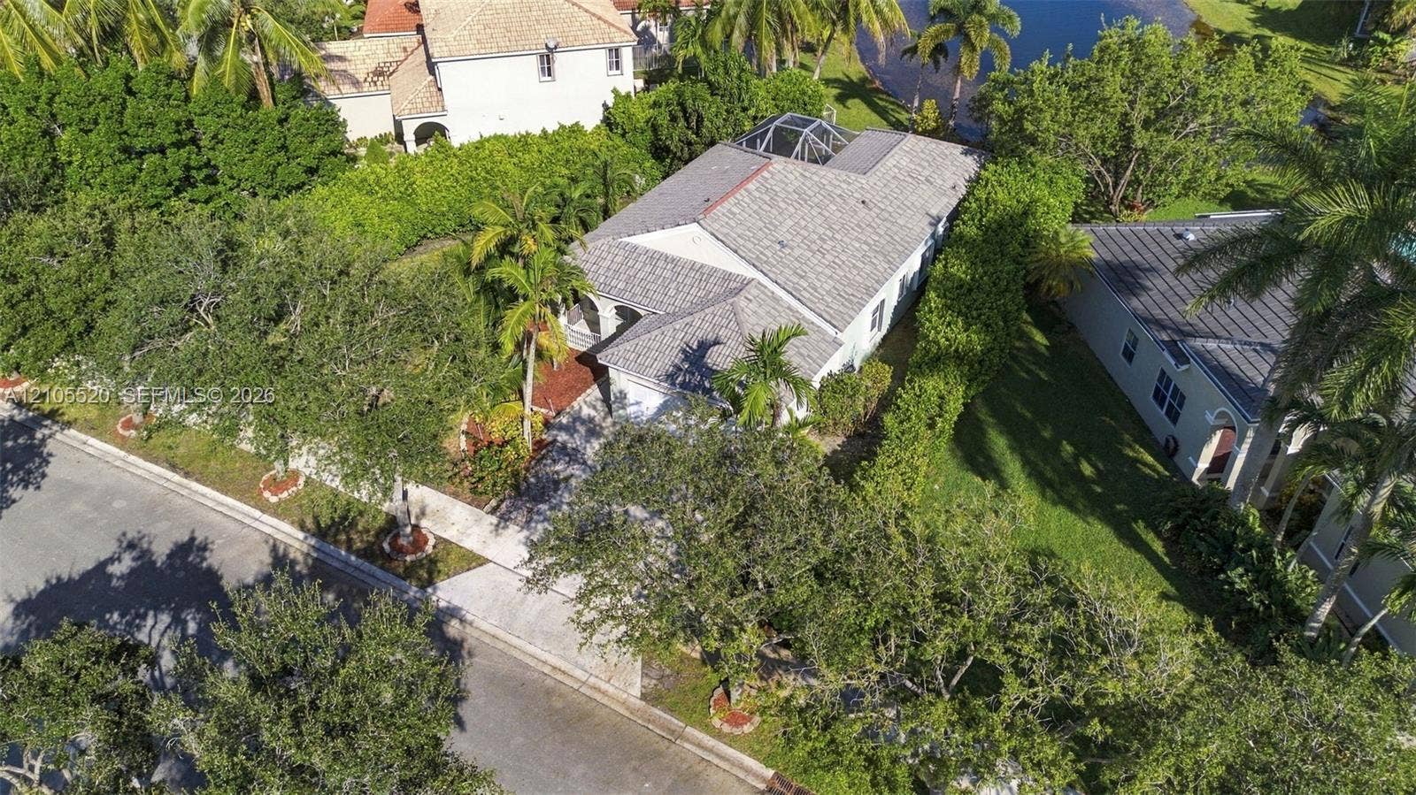 649 Willow Bend Road, Weston, Weston, FL 33327 Single-story residence featuring a shingle roof, concrete driveway, attached garage, screen-enclosed pool structure, and perimeter landscaping