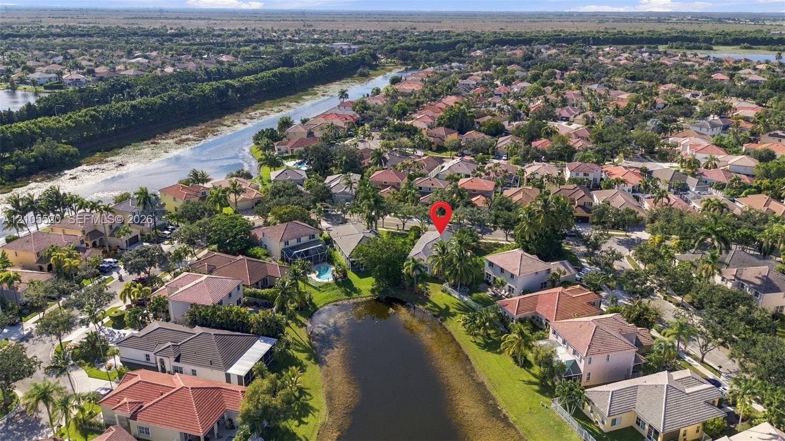 649 Willow Bend Road, Weston, Weston, FL 33327 Aerial perspective of a multi-story residence featuring a tile roof, situated on a lot bordering a community pond with mature landscaping and palm trees